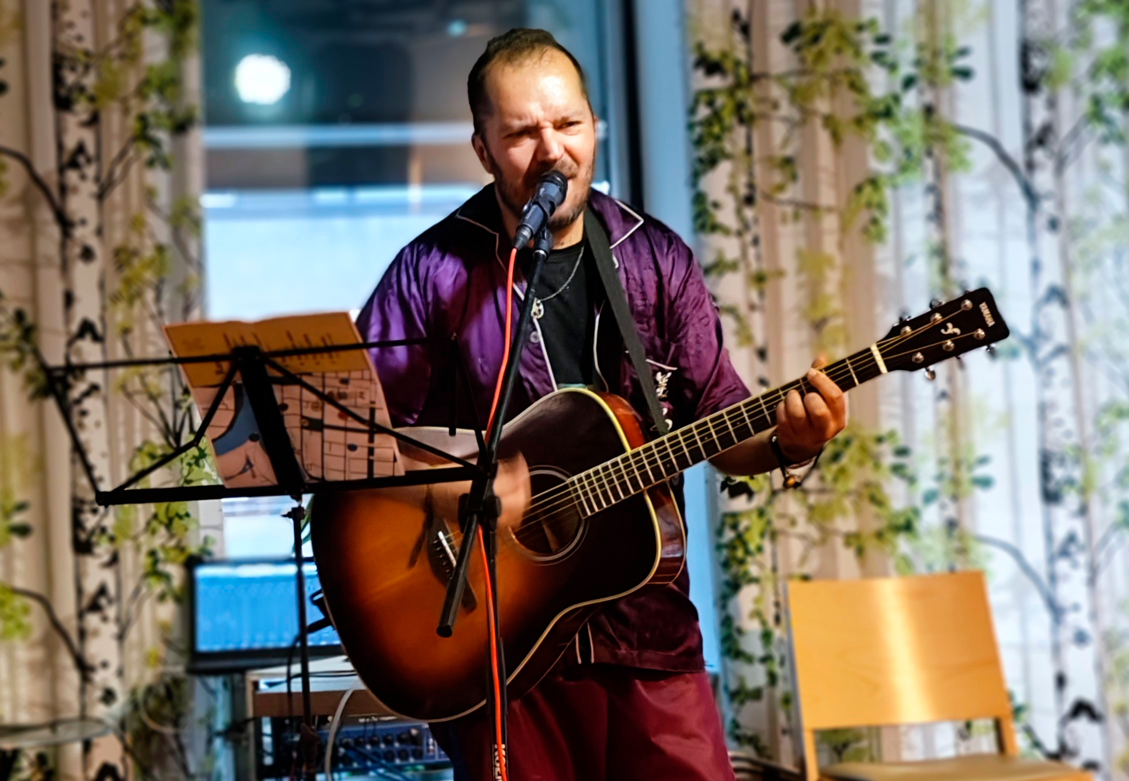 Riku Turpeinen soittaa kitaraa ja laulaa lavalla, nuottiteline edessä.